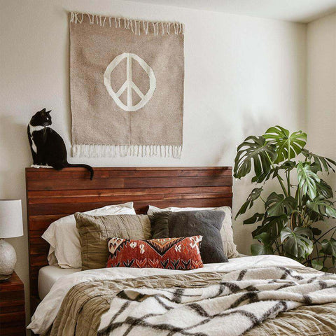 Peace Blanket Art by Trek Light as wall tapestry above bed with cat, creating a tranquil bedroom setting.