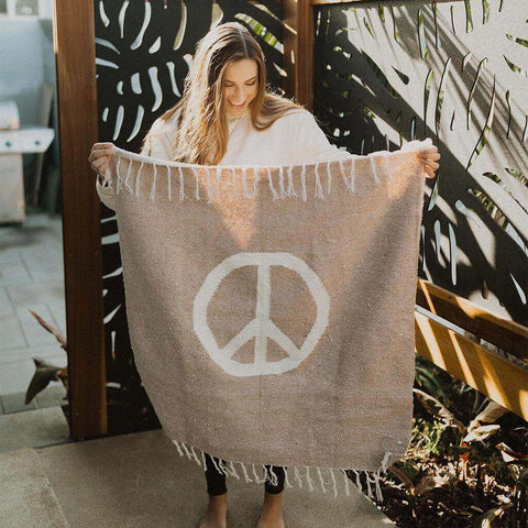 Woman holding Trek Light Peace Blanket Art with peace symbol, perfect as tapestry or cozy blanket.