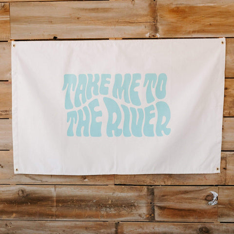 Large "Take Me To The River" canvas flag by Trek Light on wooden wall; hand-screened ink, 10oz cotton canvas.