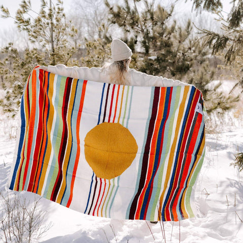 Person holding colorful Halley's Comet Blanket by Trek Light in snowy outdoors