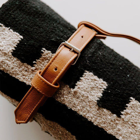 Stylish Trek Light leather blanket carrier holding a cozy black and beige blanket, perfect for on-the-go adventures.