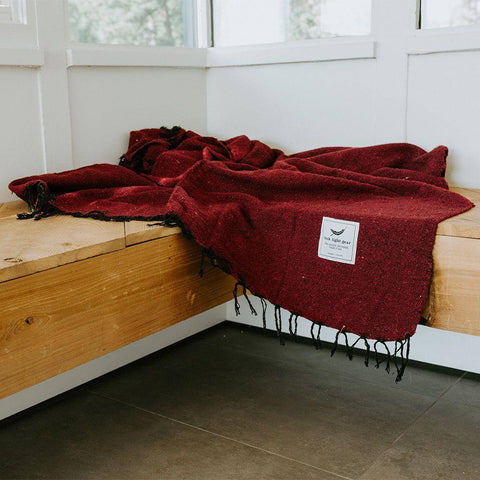 Cozy Napa Blanket in rich red, handwoven from recycled materials by Trek Light. Perfect for naps and eco-conscious relaxation.