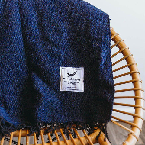 Navy Trek Light Newport Blanket draped over a chair, perfect for Newport Jazz or Folk Festivals. Handwoven elegance.