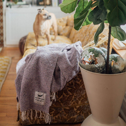 Cozy lavender Sonoma Blanket on a sofa, handwoven from recycled clothing materials, perfect for creating a beautiful, serene space. By Trek Light.