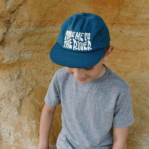 Child wearing blue 'Take Me To The River' kids hat by Trek Light, perfect for outdoor adventures.