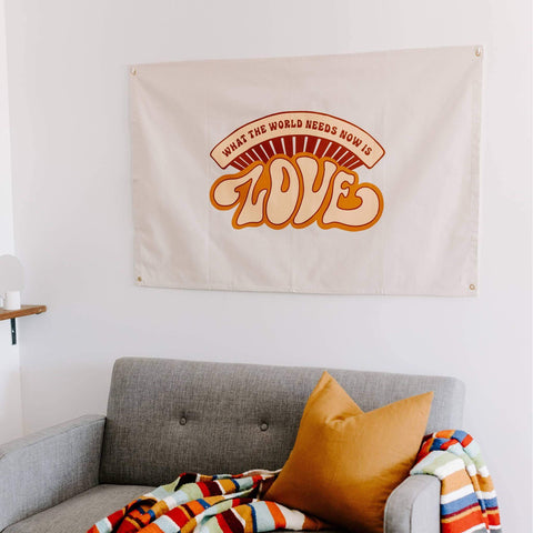 Trek Light "What The World Needs Now" canvas flag with bold 'LOVE' text, hand-screened on natural cotton. Wall decor with grommets.