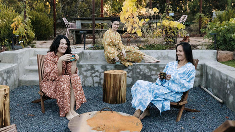 Three people relaxing outdoors in Trek Light robes, enjoying a peaceful moment surrounded by nature. Perfect blend of style and comfort.