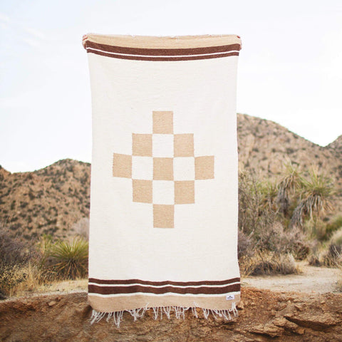 Beautiful handwoven North Star blanket, made from recycled clothing, displayed outdoors. Versatile, cozy, and sustainable. By Trek Light.
