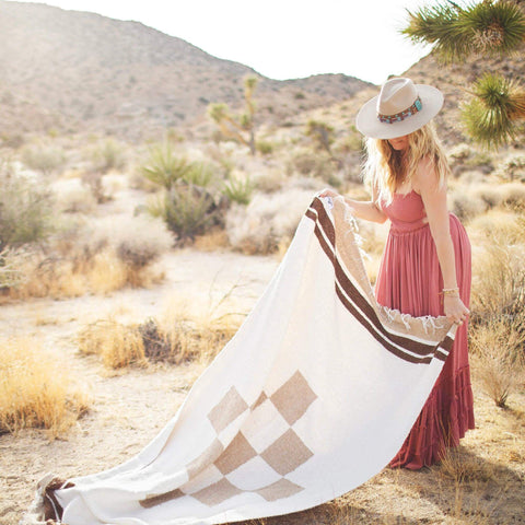 Beautiful handwoven North Star blanket in a desert setting, made from recycled clothing materials, showcasing its cozy versatility. By Trek Light.