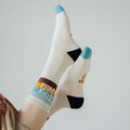 Person wearing Stay Wild socks with colorful design, emphasizing Trek Light comfort and style.