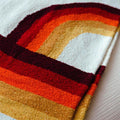 Colorful Trek Light Bowie Blanket with vintage rainbow design, made from recycled materials, folded on a soft surface.