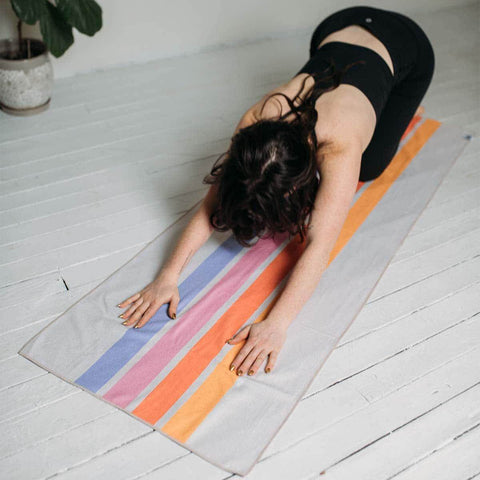 Yoga session with Trek Light Divided Sky Yoga Towel made from recycled materials, showcasing grip and absorbency in child pose.