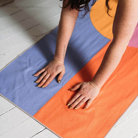 Person using Divided Sky Yoga Towel by Trek Light, eco-friendly and made from recycled materials. Waffle texture enhances grip and stability.