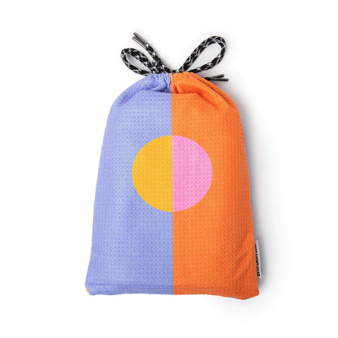 Vibrant Trek Light Divided Sky Yoga Towel with compact storage pouch, featuring colorful orange and purple design.