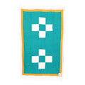 Dolly Blanket by Trek Light, handwoven from 100% recycled materials, featuring a teal design with cross patterns and fringe edges.