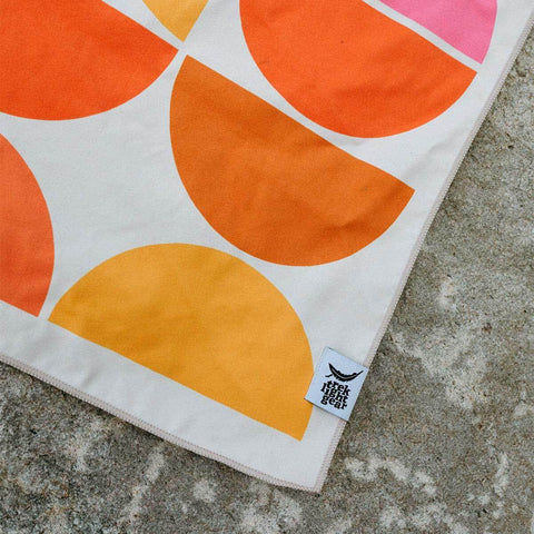 Colorful geometric pattern blanket by Trek Light on a textured stone surface.