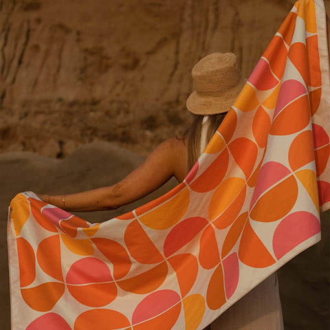 Person holding Half Moon Wander Towel with colorful geometric pattern, made from recycled materials by Trek Light, ideal for travel.