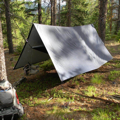 V9 Strong Tarp by Trek Light set up in the woods as a hammock rain fly, providing durable shelter for outdoor camping adventures.