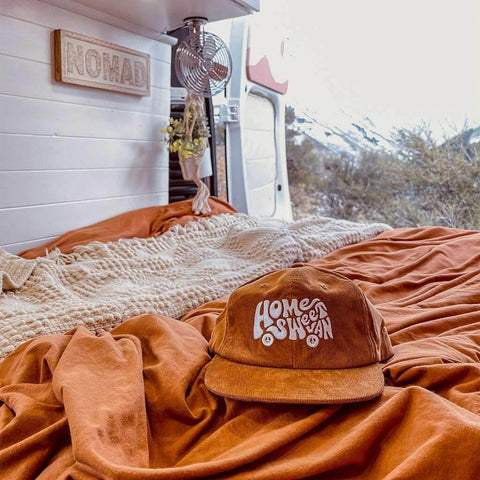 Trek Light Home Sweet Van corduroy hat in cozy van interior with mountain view, perfect for van life enthusiasts.