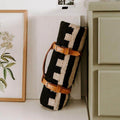 Stylish Trek Light leather blanket carrier holding a rolled black and white blanket, resting against a shelf.
