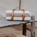 Artisan Trek Light leather blanket carrier with striped blanket, perfect for stylish travel and outdoor adventures.