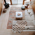 Cozy living room with a striped blanket, geometric rug, sofa, and wood-burning stove, featuring a modern, rustic decor style.