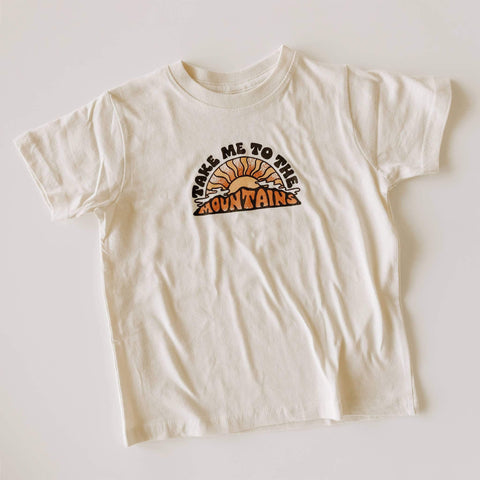 White kids T-shirt with "Take Me To The Mountains" text and mountain graphic, made from soft 100% cotton. Perfect for outdoor play. Trek Light.
