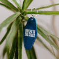 Retro 'Take Me To The River' key tag with Trek Light. Perfect for vintage hotel or motel vibes, hanging on a green plant.