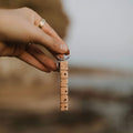 Hand holding Trek Light WANDER wood keychain with nickel ring, perfect gift idea. Elegant hand-cut design for keys.